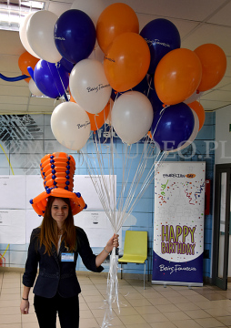 Hostessa w kapeluszu z balonów rozdaje balony reklamowe.